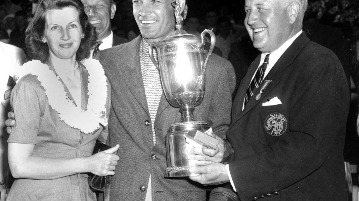 FILE - In this June 11, 1950, file photo, Ben Hogan, center, smiles over a crowd and poses with his wife, Valerie, left, as he receives the U.S. Open Golf Championship trophy from James D. Standish, Jr., Detroit president of the United States Golf Association, in Ardmore, Pa.