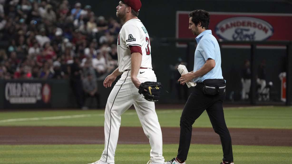 Arizona Diamondbacks pitcher Corbin Burnes, left, leaves a baseball game against the Washington Nationals in the fifth inning Sunday, June 1, 2025, in Phoenix.