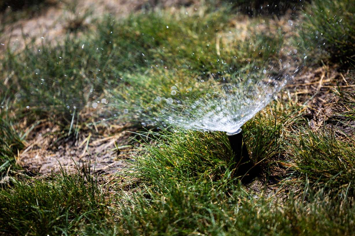 Sprinklers spray water in the Capitol Hill neighborhood in Salt Lake City on Monday.