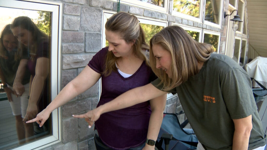 Cheryl Rubink, left, and Morgan Rubink, right, point out where a black bear left a paw mark on a cabin window.