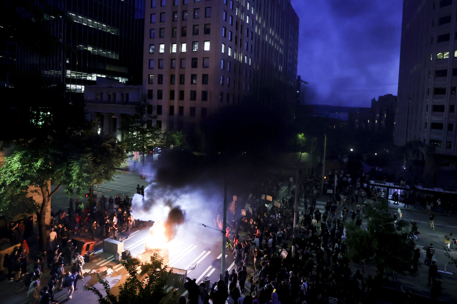 Protestors surround a dumpster that was set on fire in front of the Henry M. Jackson Federal Building during a protest against federal immigration arrests, Wednesday in Seattle.