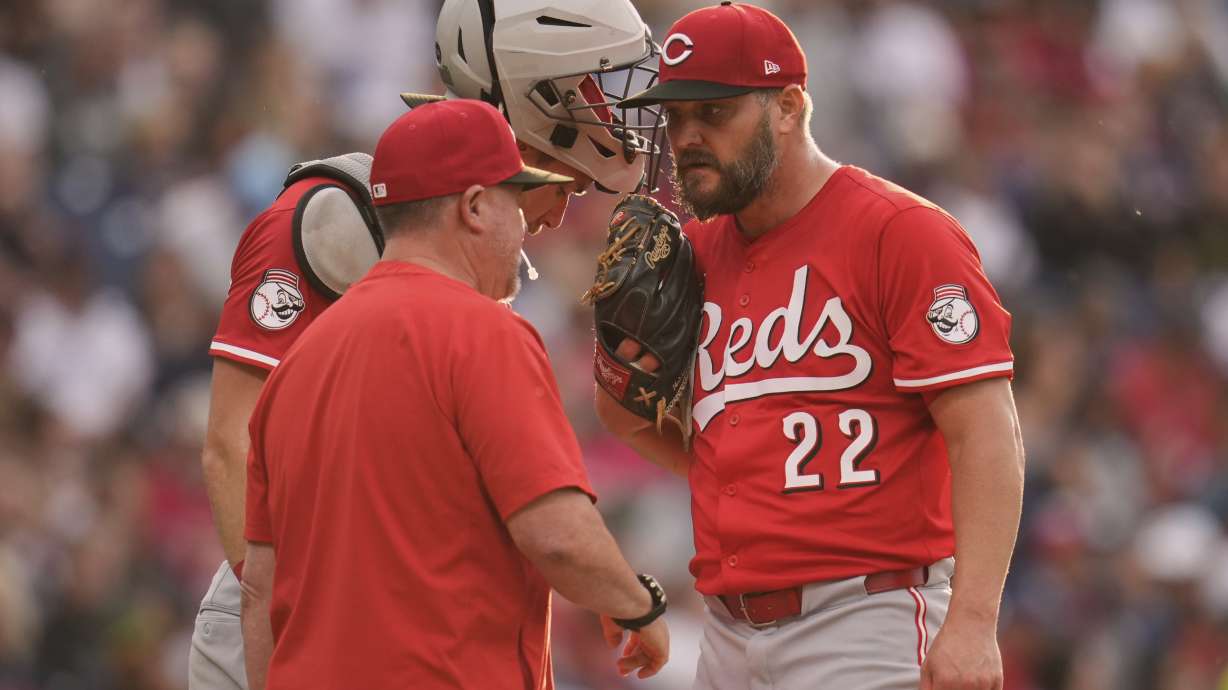 Cincinnati Reds pitching coach Derek Johnson, left, talks with catcher Tyler Stephenson, center, and starting pitcher Wade Miley (22) in the third inning of a baseball game in Cleveland, Monday, June 9, 2025.