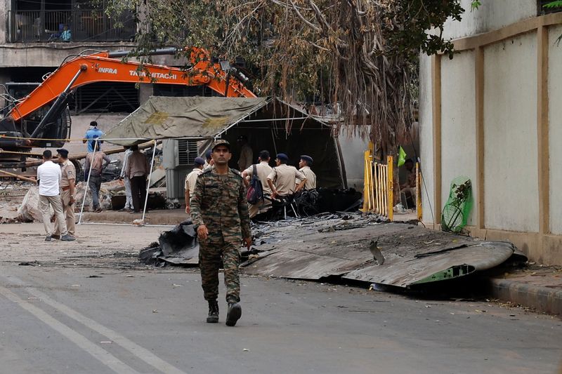 A security personnel walks near the crash site of the Air India Boeing 787-8 Dreamliner plane that crashed during take-off from an airport, in Ahmedabad, India, Friday.