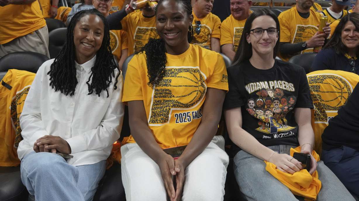 Indian Fever basketball players Caitlin Clark, right, and Aliyah Boston, center, watch during the first half of Game 4 of the NBA Finals basketball series between the Indiana Pacers and the Oklahoma City Thunder, Friday, June 13, 2025, in Indianapolis.