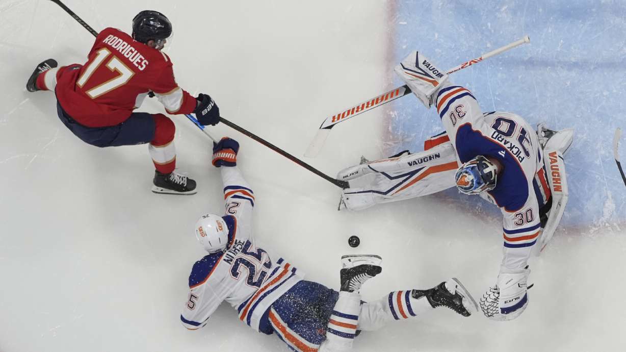 Florida Panthers right wing Mackie Samoskevich (25) defends Florida Panthers center Evan Rodrigues (17) as goaltender Calvin Pickard (30) deflects a shot on goal during the third period of Game 4 of the NHL hockey Stanley Cup Final Friday, June 13, 2025, in Sunrise, Fla.