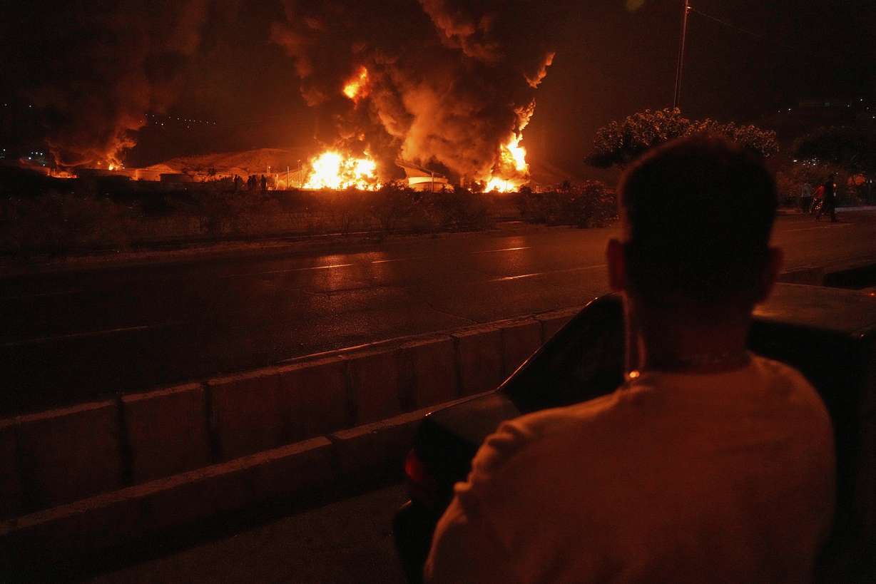 A man looks at flames rising from an oil storage facility after it was hit by an Israeli strike in Tehran, Iran, early Sunday. The Shahran oil depot was targeted by an Israeli strike, but Iranian officials said the situation was under control.