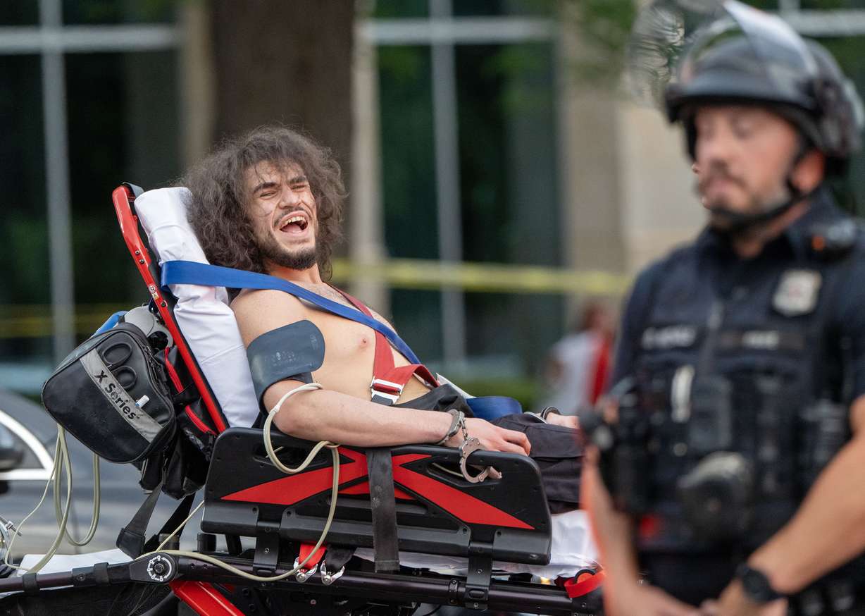A man is taken away in handcuffs on a gurney and yells that he was shot during the “No Kings” protest and march in Salt Lake City on Saturday.