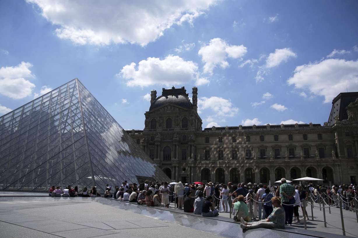 Tourists wait in line outside the Louvre museum which failed to open on time Monday, in Paris.