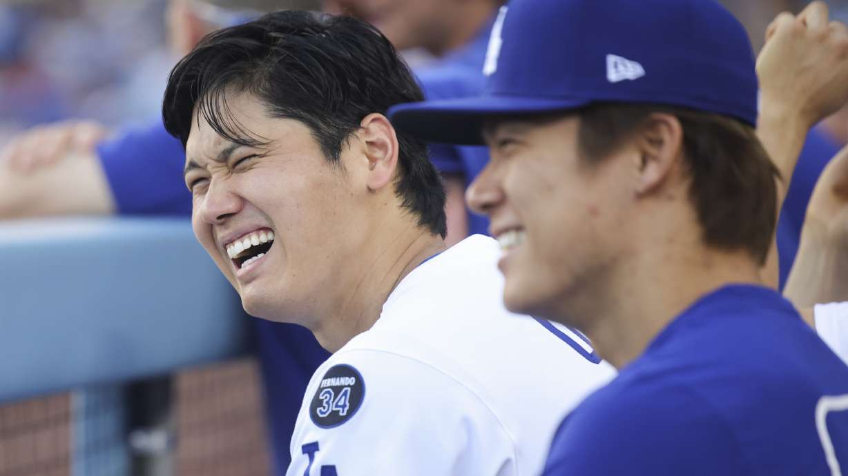 Los Angeles Dodgers' Shohei Ohtani reacts alongside Yoshinobu Yamamoto during the eighth inning of a baseball game against the San Francisco Giants in Los Angeles, Sunday, June 15, 2025.