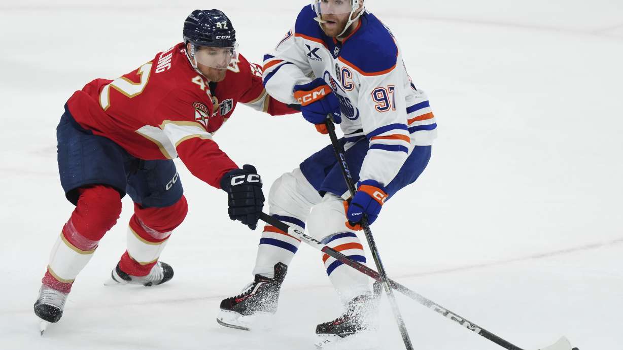 Florida Panthers' Gustav Forsling (42) pokes the puck away from Edmonton Oilers' Connor McDavid (97) during the second period in Game 3 of the NHL hockey Stanley Cup finals in Sunrise, Fla., Monday, June 9, 2025.