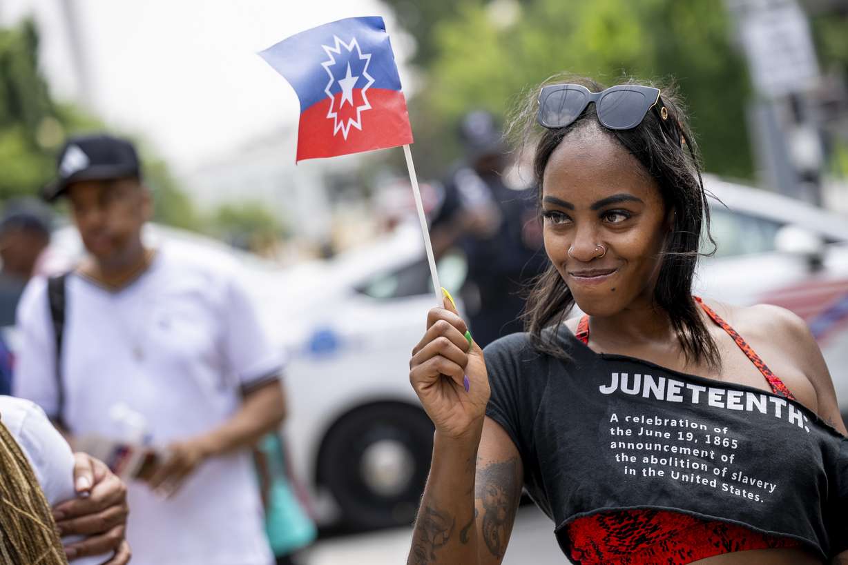 Chelsea Andrews, of Washington, waves the Juneteenth flag during a Juneteenth celebration at Black Lives Matter Plaza in Washington, June 19, 2023.