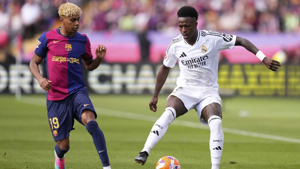 Real Madrid's Vinicius Junior, right, and Barcelona's Lamine Yamal compete for the ball during the Spanish La Liga soccer match between Barcelona and Real Madrid at the Lluis Companys Olympic Stadium in Barcelona, Spain, Sunday, May 11, 2025.