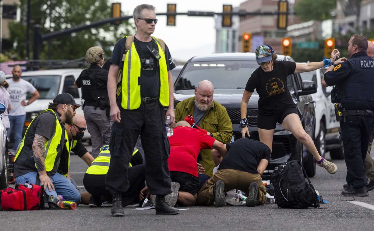 People, including "peacekeepers," rush to give medical assistance to a man shot during a “No Kings” protest and march in Salt Lake City on Saturday. Police are investigating whether the peacekeepers were appointed by protest organizers, volunteered, were hired or were self-appointed. A peacekeeper shot and killed an "innocent bystander" while also shooting a man running toward the crowd with a gun, police say.