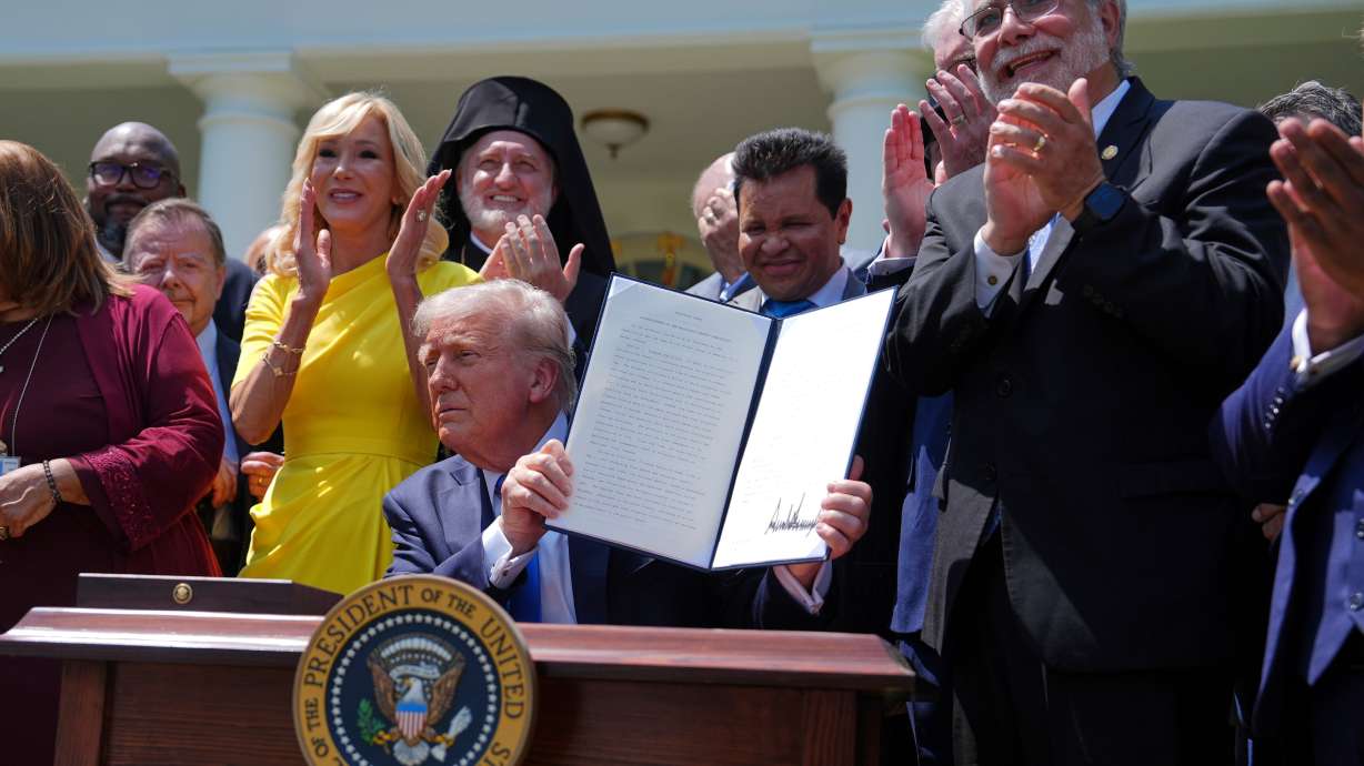 President Donald Trump, surrounded by religious leaders, holds up a signed executive order establishing the Religious Liberty Commission, during a National Day of Prayer event in the Rose Garden of the White House, May 1, in Washington.