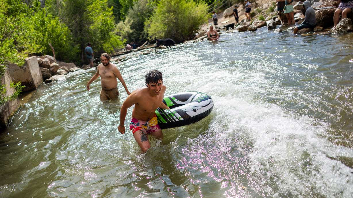 Lane Austin, of Salt Lake City, center, laughs after riding down Parley's Canyon drainage pipeline in a water tube on June 1. Hotter temperatures are forecast for the next few days, prompting multiple advisories.
