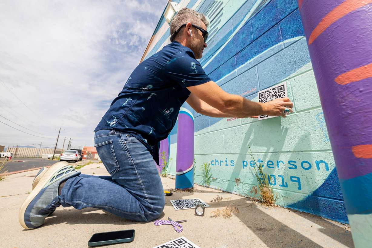 Chris Peterson affixes a QR code to part of his "Space Trout and Utopia Mural Project” in Salt Lake City on June 5. Peterson said the murals serve as gathering and engagement tools for the community.