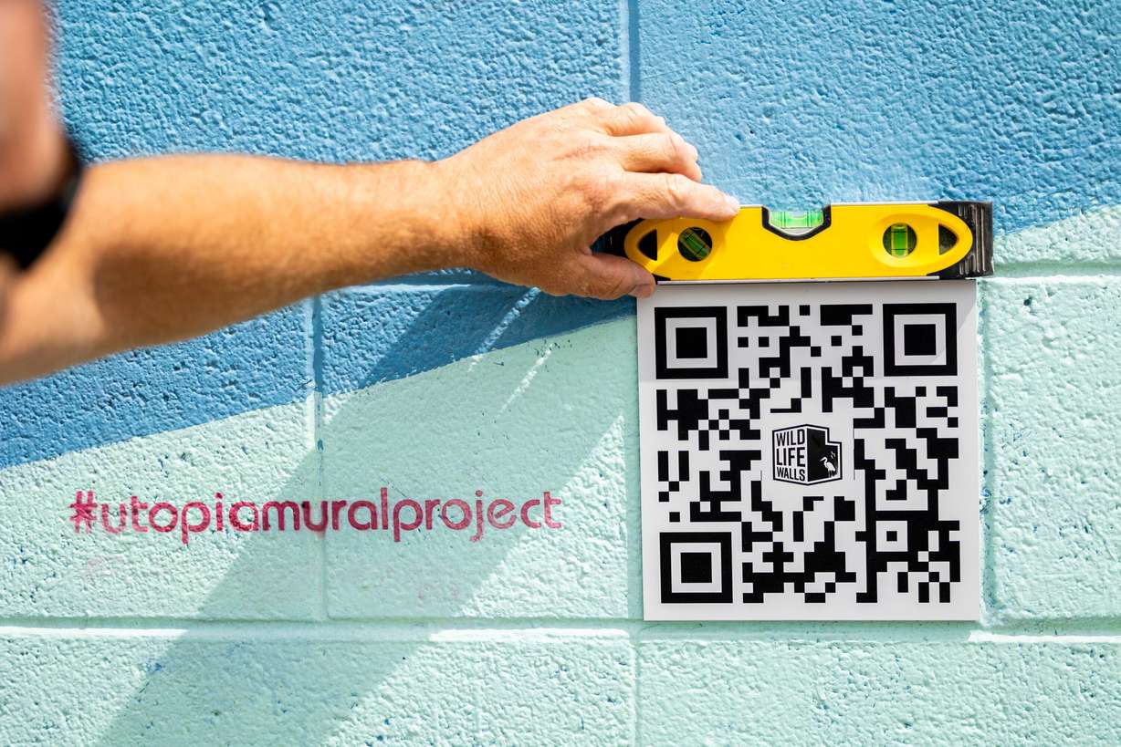 Chris Peterson affixes a QR code to part of his "Space Trout and Utopia Mural Project” in Salt Lake City on June 5. The project runs social media giveaways to encourage people to visit the sites and share experiences.