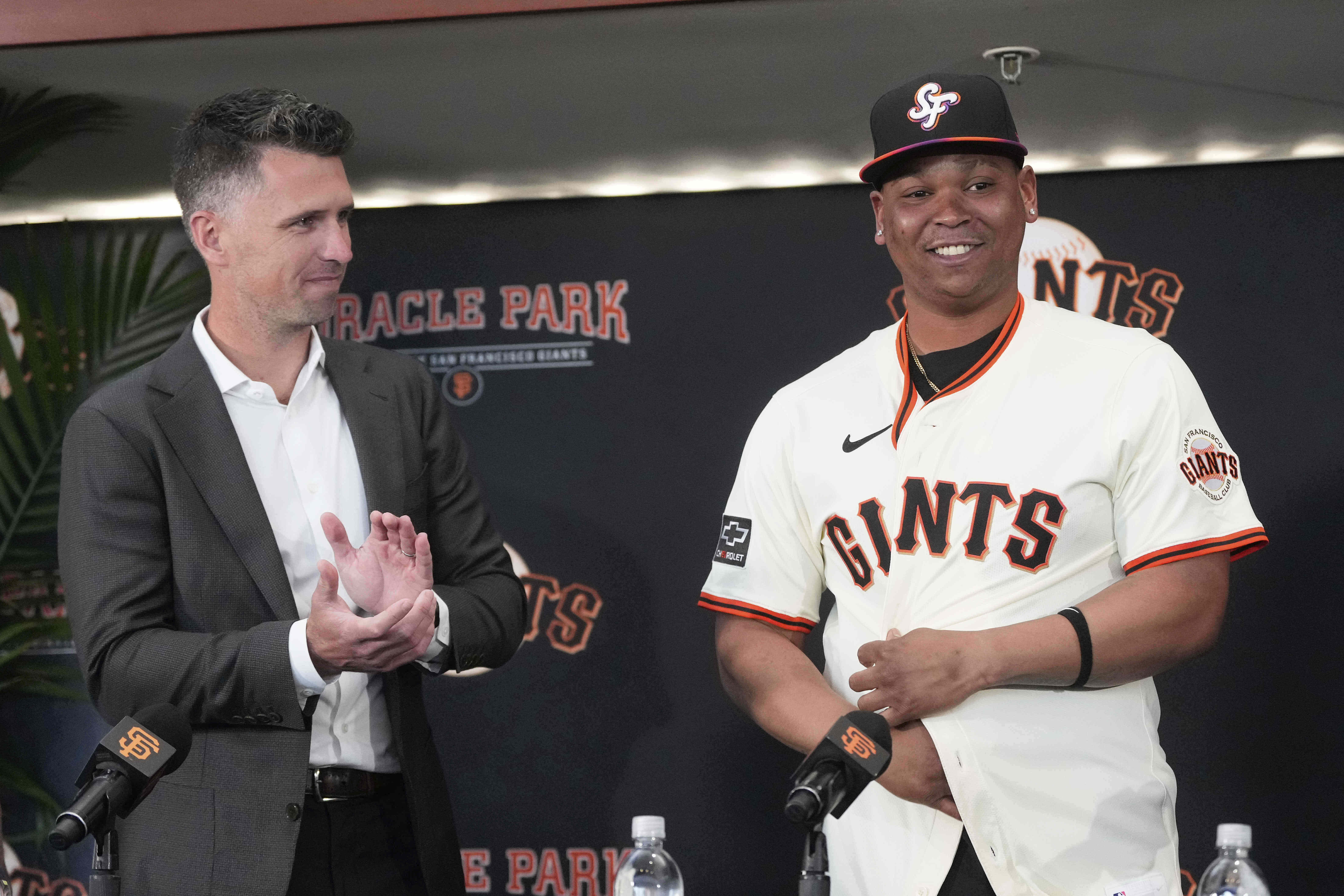 San Francisco Giants' Rafael Devers, right, smiles next to President of Baseball Operations Buster Posey at a news conference before a baseball game between the Giants and the Cleveland Guardians in San Francisco, Tuesday, June 17, 2025.