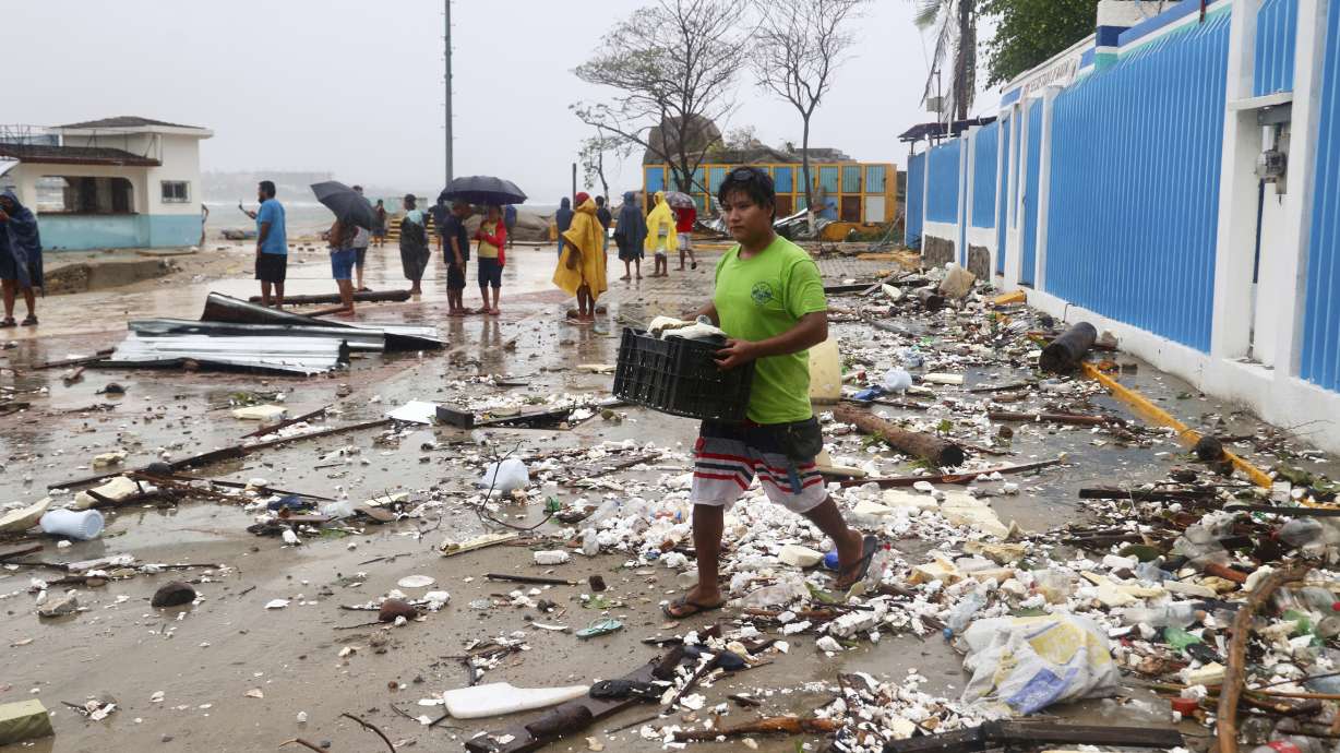 A person walks through debris after Hurricane Erick hit near Puerto Escondido, Oaxaca state, Mexico, Thursday. At least one person was confirmed dead Friday as officials continue to assess damage from the storm.