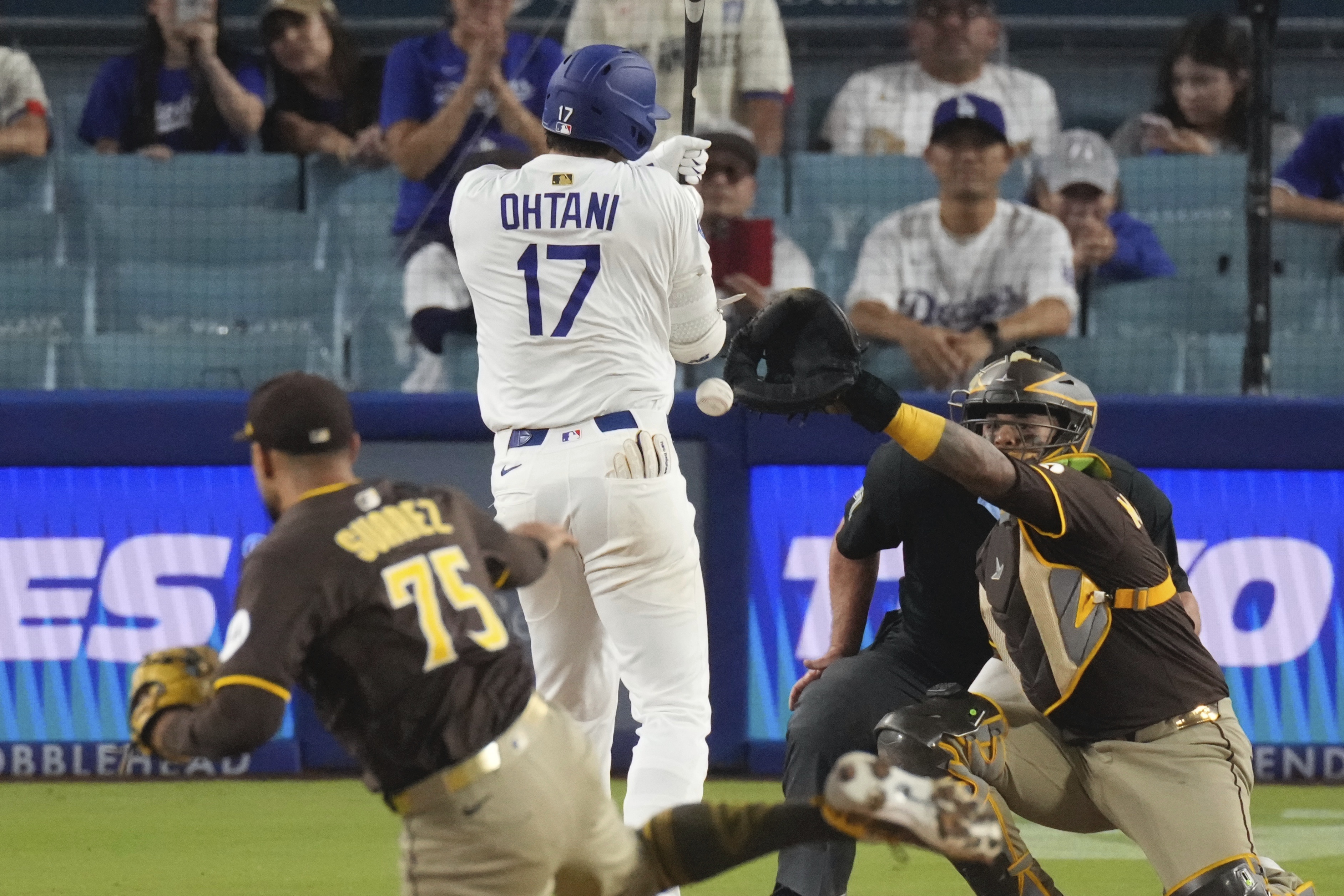 Los Angeles Dodgers' Shohei Ohtani, center is hit by a pitch thrown by San Diego Padres relief pitcher Robert Suarez, left as catcher Martin Maldonado watches during the ninth inning of a baseball game Thursday, June 19, 2025, in Los Angeles.