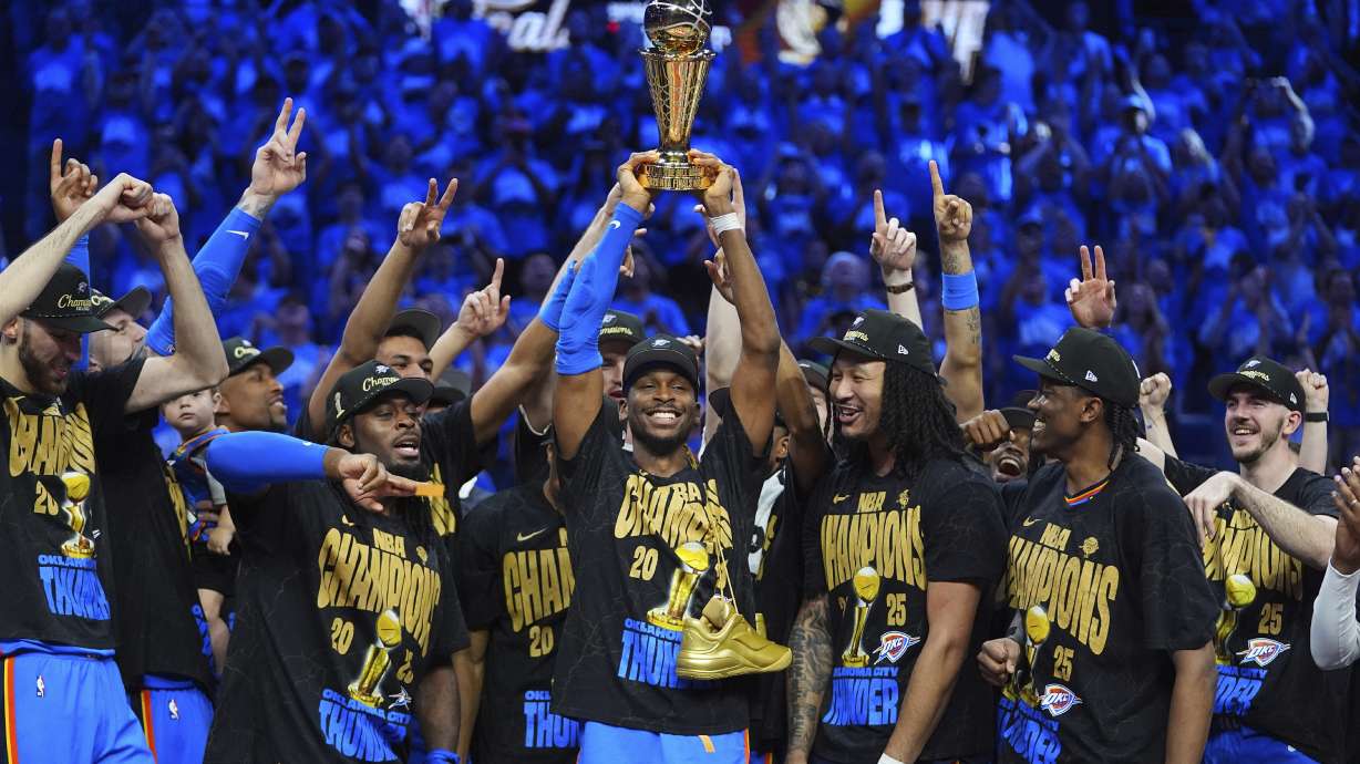 Oklahoma City Thunder guard Shai Gilgeous-Alexander, center, holds up the MVP trophy as he celebrates with his team after they won the NBA basketball championship with a Game 7 victory against the Indiana Pacers Sunday, June 22, 2025, in Oklahoma City.