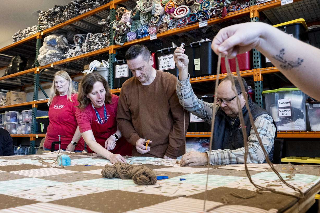 Carol Jensen, third from left, a volunteer from Vineyard, helps Jason Paas and Ken Follett, both volunteers from Asphalt Zipper, work on a quilt at Stitching Hearts Worldwide’s headquarters in Pleasant Grove on Jan. 7.