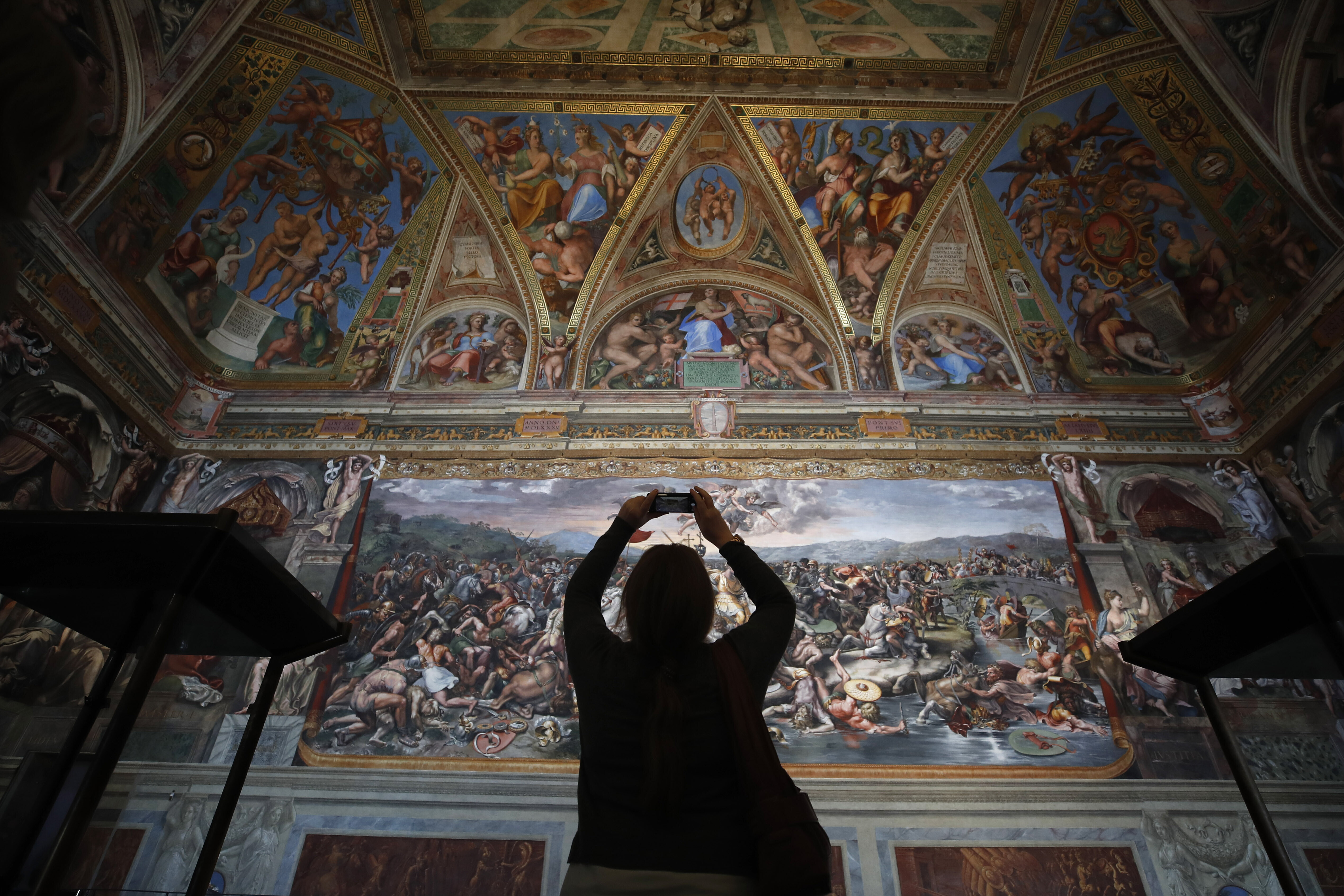 A visitor admires a Raphael Room inside the Vatican Museums at the Vatican, on May 3, 2021. The museum unveiled the last restored Raphael Room Thursday after a 10-year cleaning project.