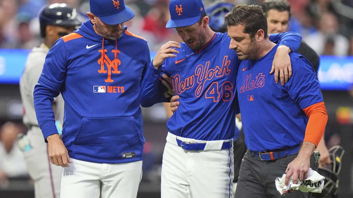 New York Mets pitcher Griffin Canning, center, is helped off the field by head athletic trainer Joseph Golia, right, and pitching coach Jeremy Hefner during the third inning of a baseball game against the Atlanta Braves Thursday, June 26, 2025, in New York.
