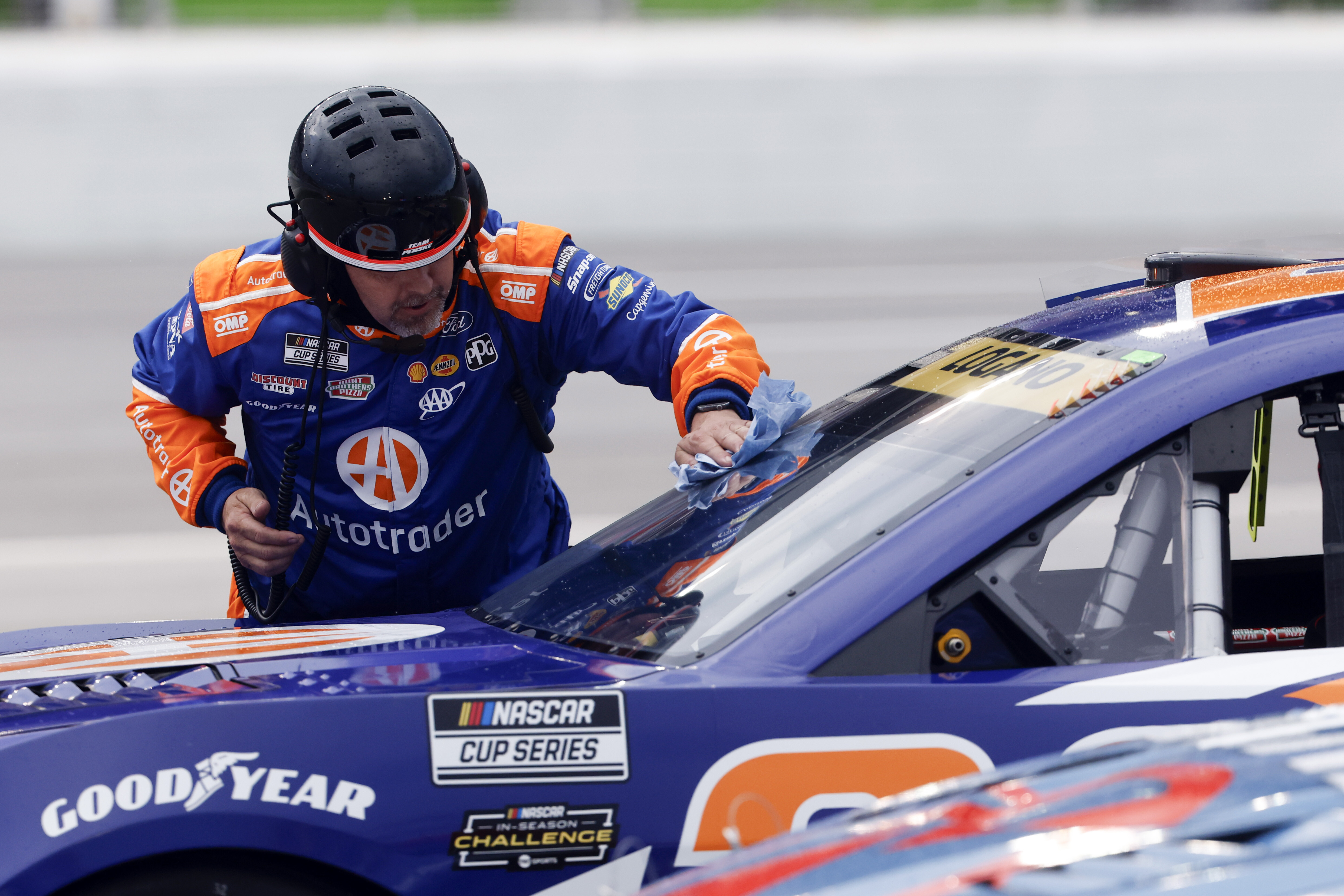 A crew member for driver Joey Logano wipes off water from the windshield during a red flag weather delay in a NASCAR Cup Series auto race, Saturday, June 28, 2025, in Hampton, Ga.