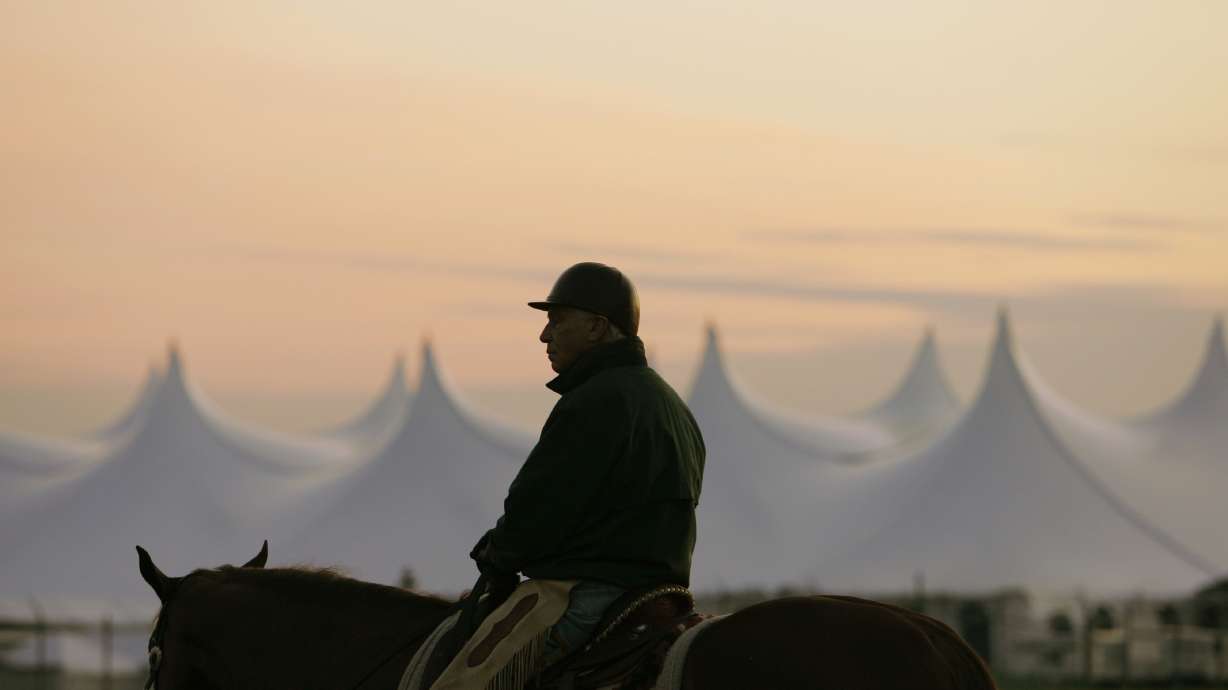 FILE - Trainer D. Wayne Lukas sits atop his horse as he watches morning workouts against the backdrop of a large tent set up in the infield before sunrise at Churchill Downs in Louisville, Ky., April 25, 2009.