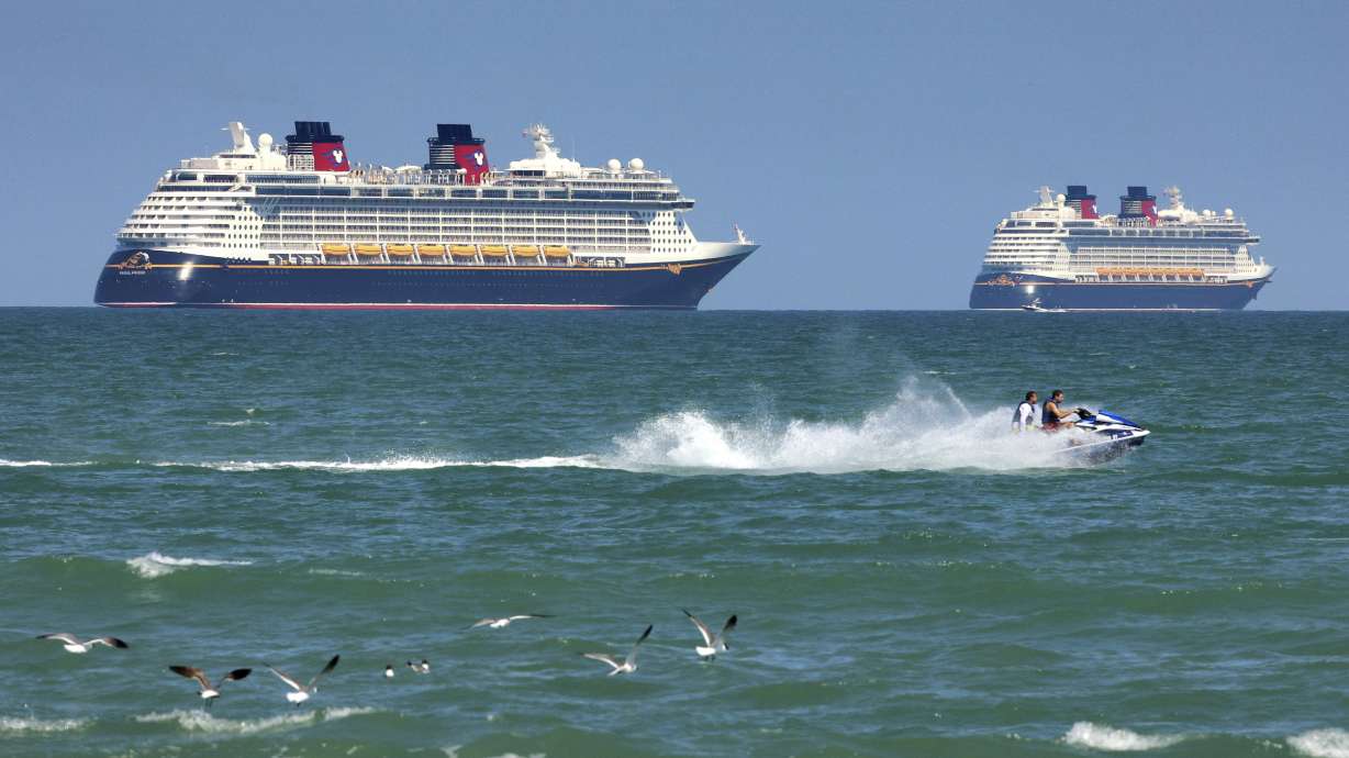 Jet skiers pass the Disney Cruise Line ships "Fantasy," left, and "Dream" on the horizon off of Cocoa Beach, Fla., March 24, 2021.