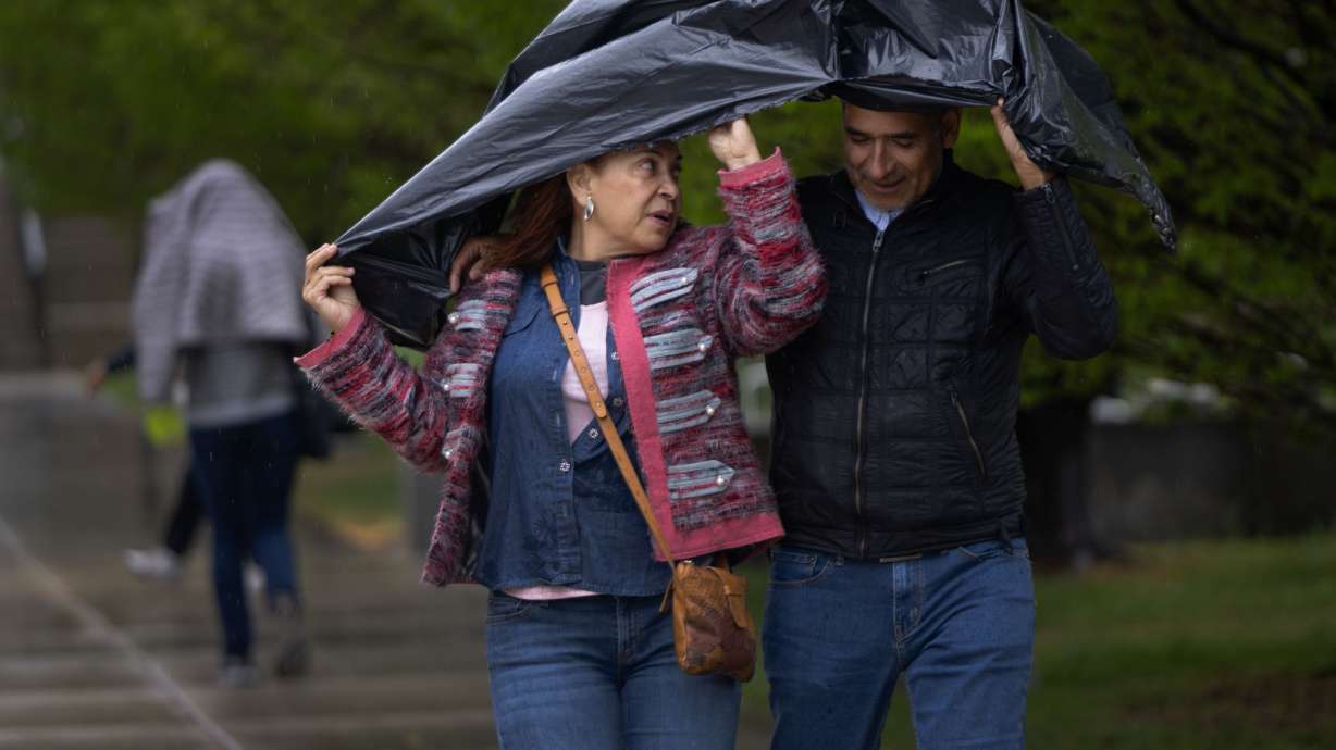 Patricia Marin and Duvan Guerrero use a garbage bag to protect themselves from the rain in Salt Lake City on April 26, 2024. A small monsoonal pattern could produce scattered showers across Utah through Thursday.