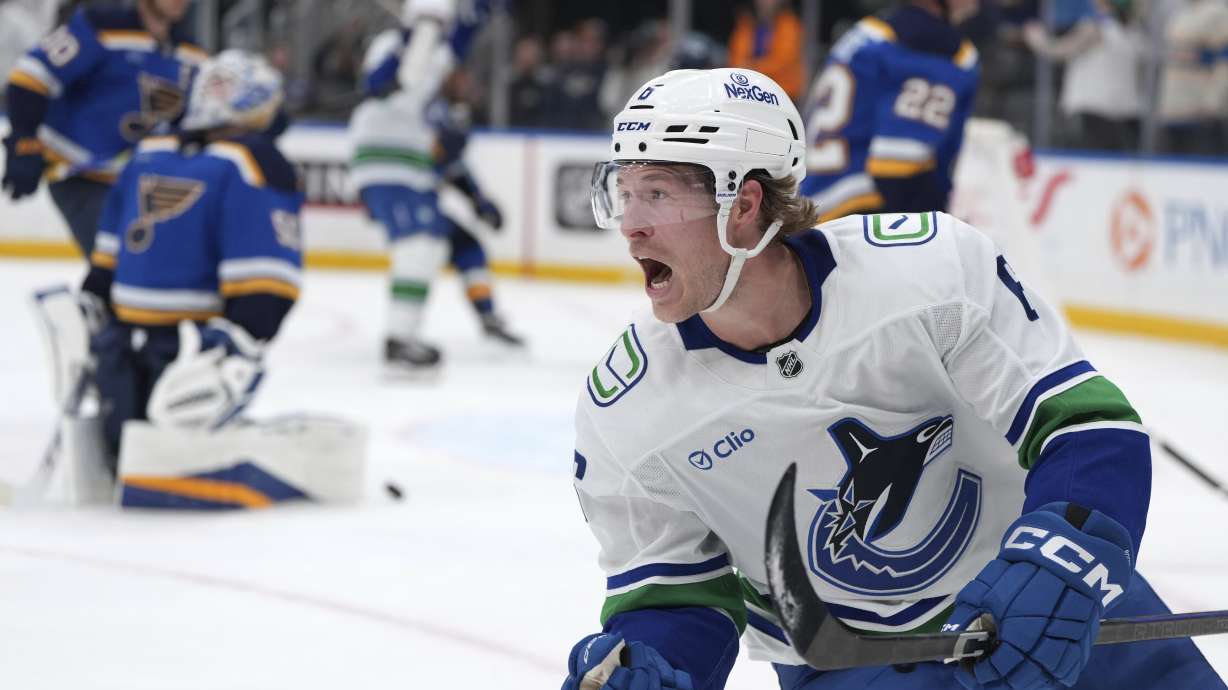 FILE - Vancouver Canucks' Brock Boeser, right, celebrates after scoring past St. Louis Blues goaltender Jordan Binnington, left, during the third period of an NHL hockey game, March 20, 2025, in St. Louis.