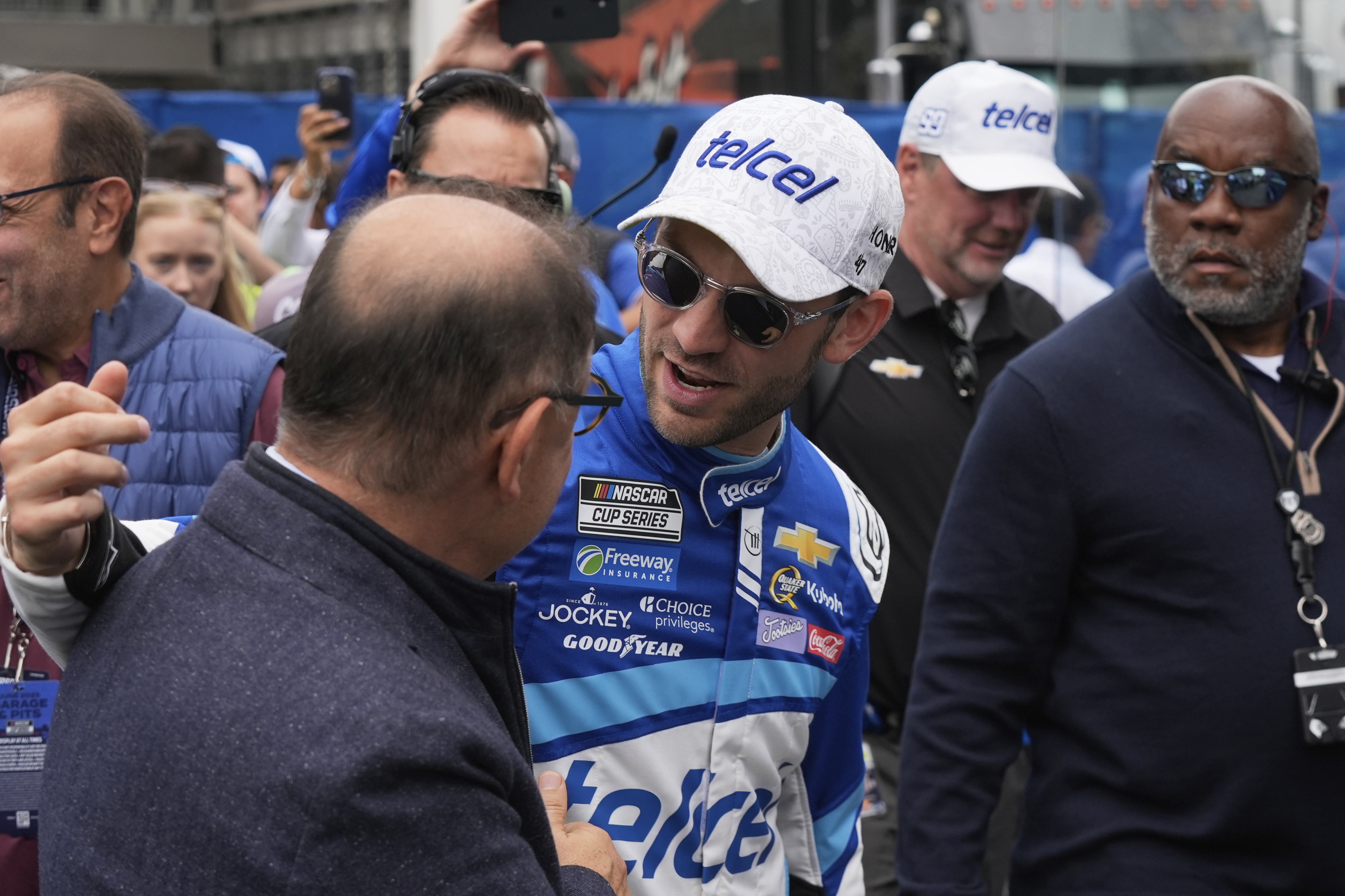 Daniel Suarez, center greets a man before a NASCAR Cup Series auto race at Hermanos Rodríguez race track in Mexico City, Sunday, June 15, 2025.