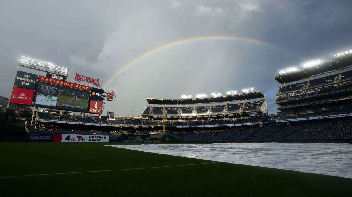 A rainbow forms while a tarp is on the field as the start of a baseball game between the Washington Nationals and the Colorado Rockies is delayed due to weather at Nationals Park, Wednesday, June 18, 2025, in Washington.