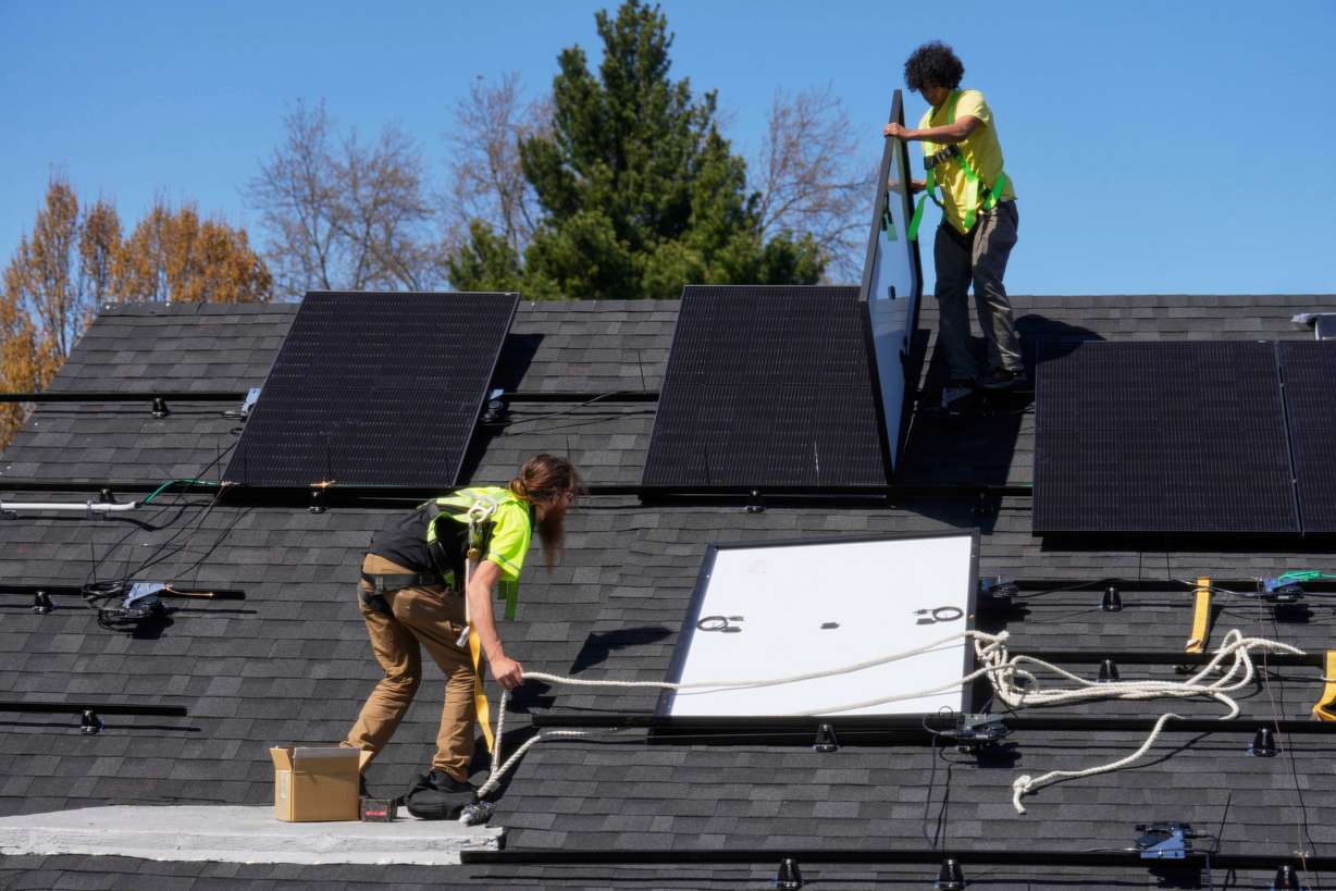 Theodore Tanczuk and Brayan Santos put solar panels on the roof of a home in Lakewood, Ohio, April 16. Sen. John Curtis included language in President Donald Trump's tax bill that lifts bans on proposed solar leasing.
