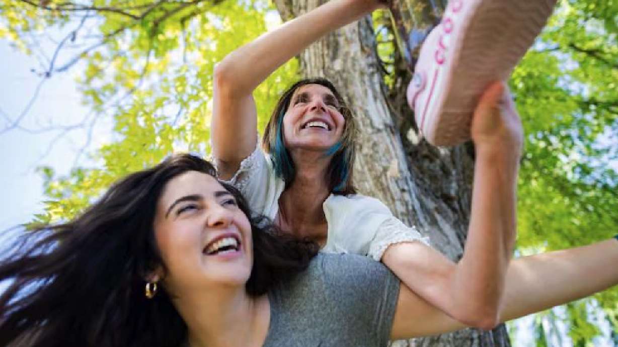 Renee DeHaan, center, who trekked to Mount Everest base camp this spring on her prosthetic leg, holds up the leg while on the back of her prosthetist and friend Quincey Brabant, left, who accompanied her on the trek, at DeHaan's home in South Jordan on June 7.