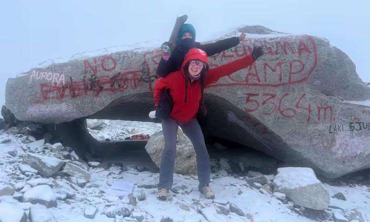 Quincey Brabant and Renee DeHaan at the famous rock fronting Everest Base Camp. Renee is hoisting her artificial leg in the air.