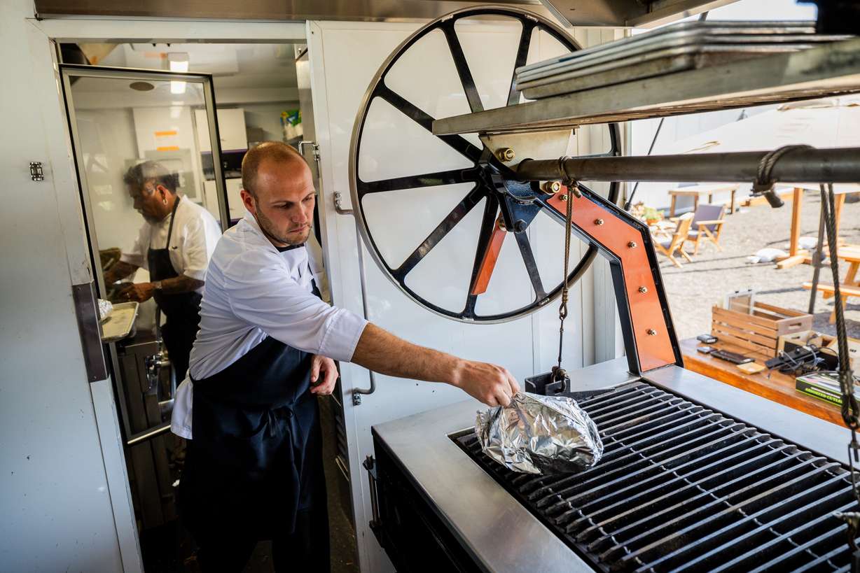 Chefs Guillermo Tellez, left, and Aaron Pae, right, prepare food inside SmokeWood, a mobile food trailer, for customers at Gracie's Farm in Wanship on Friday, June 20, 2025.