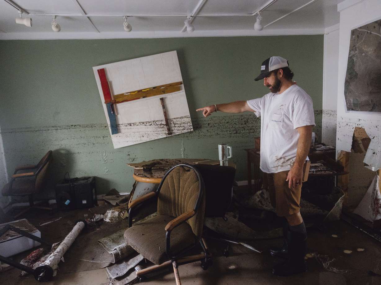 Garrett Burleson shows the damage to the office of his family's architectural business as a dirt line shows the extent of the flooding that the building faced, in Ingram on Friday.