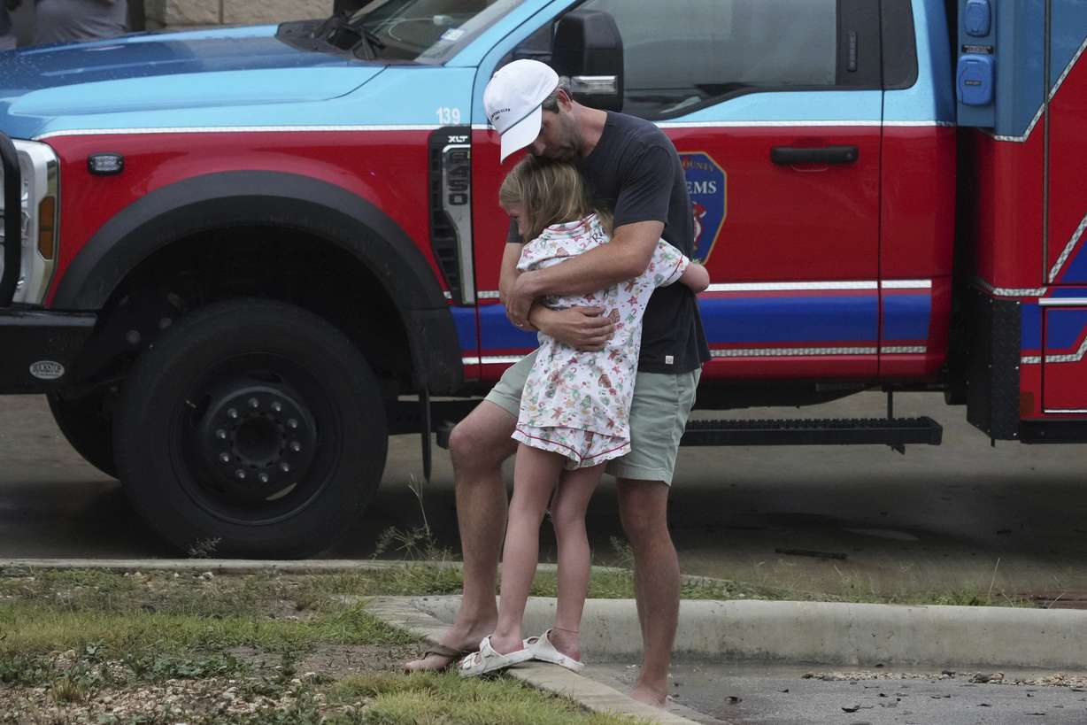 People are reunited at a reunification center after flash flooding hit the area, Friday, in Ingram, Texas.
