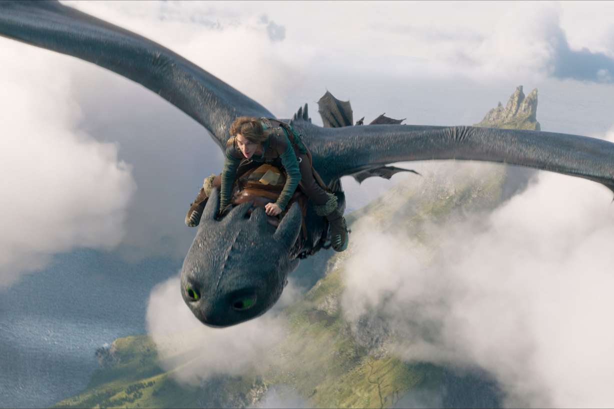 This image released by Universal Pictures shows Mason Thames, as Hiccup, riding Night Fury dragon Toothless in a scene from "How to Train Your Dragon."