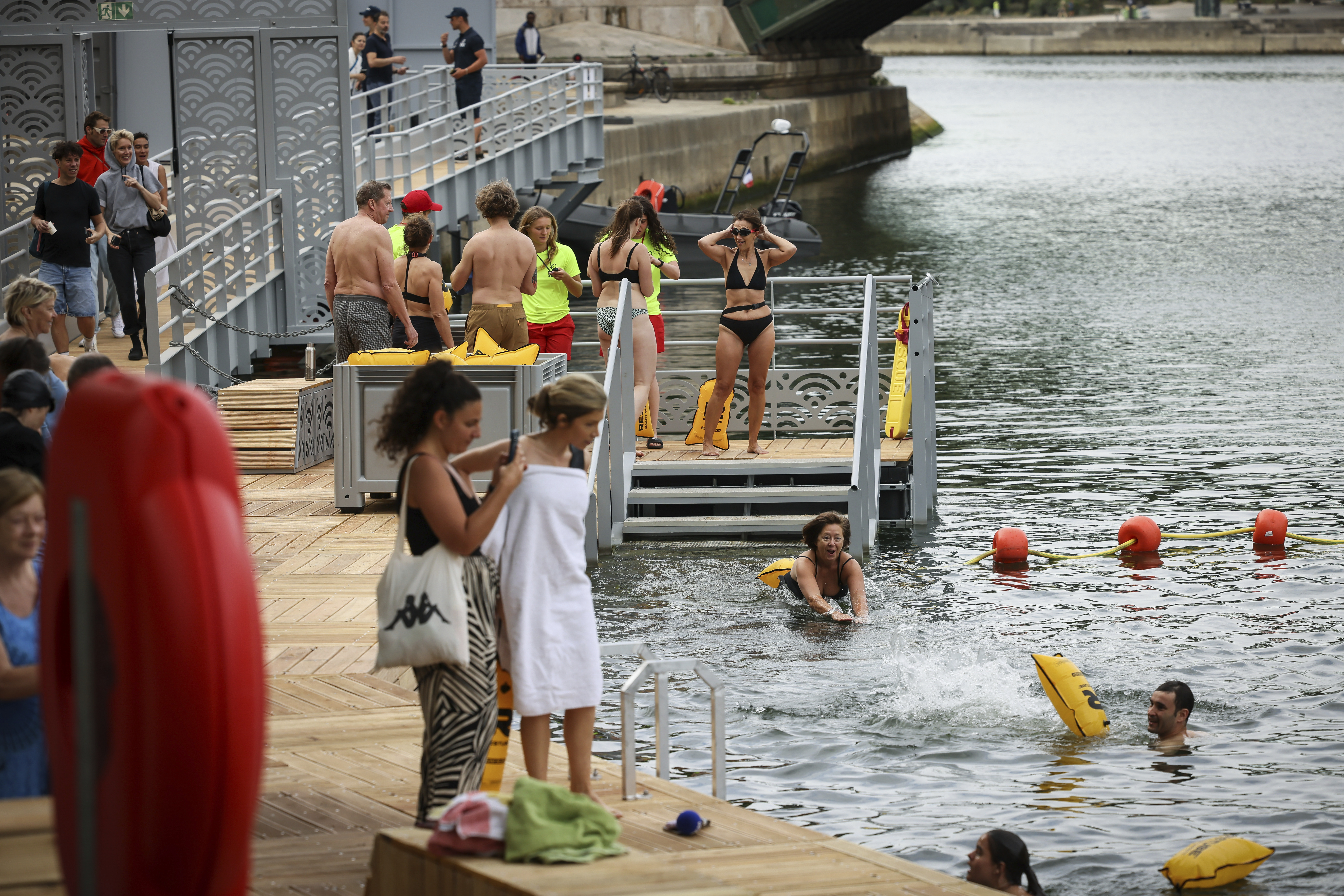 A woman dives in the water as people swim at the Pont Marie safe bathing site on the Seine river in Paris, France, Saturday, July 5, 2025, during the opening of the three Seine swimming pools, as part of the 'Paris Plages' event.
