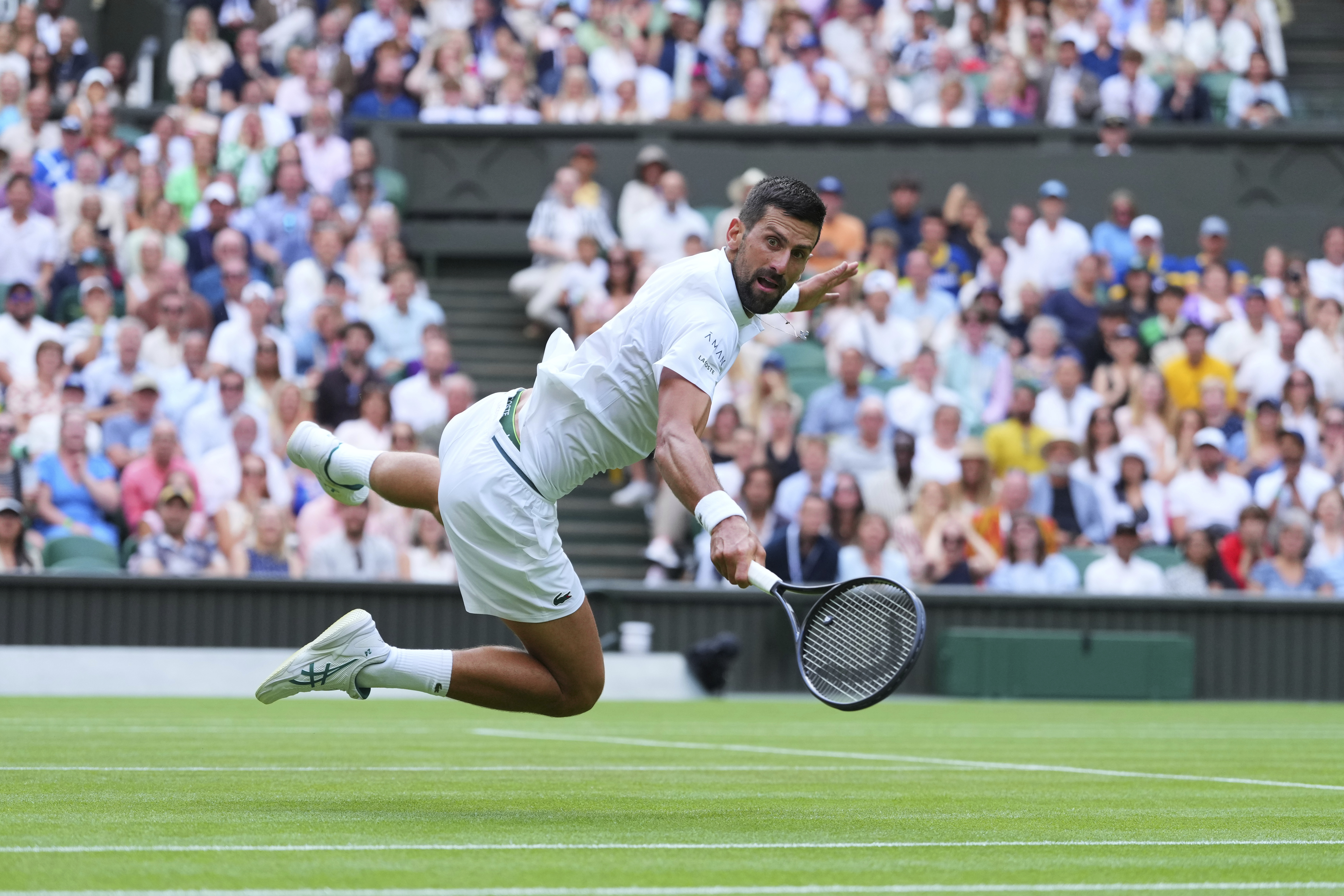 Novak Djokovic of Serbia dives to return to Miomir Kecmanovic of Serbia during a third round men's singles match at the Wimbledon Tennis Championships in London, Saturday, July 5, 2025.