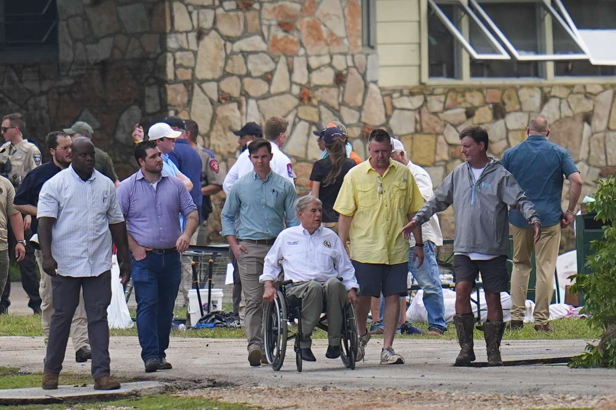 Texas Gov. Greg Abbott tours Camp Mystic along the banks of the Guadalupe River, Saturday, in Hunt, Texas. Abbott declared Sunday a day of prayer for the entire state.