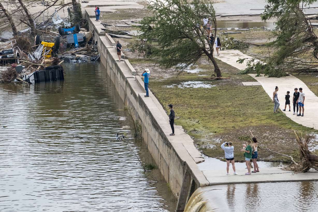 Onlookers walk along the banks of the Guadalupe River in Louise Hays Park, Saturday, in Kerrville, Texas. Officials said more than 850 people had been rescued in the past 36 hours.