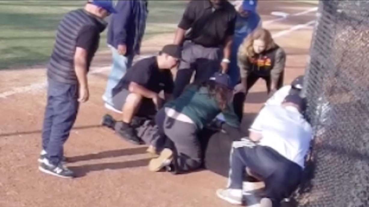 Dr. Jen Poole, in the green sweater, prepares to perform CPR on Little League umpire Jeff Hiserodt. Poole ended up saving Hiserodt's life after he suffered a heart attack during a recent game.