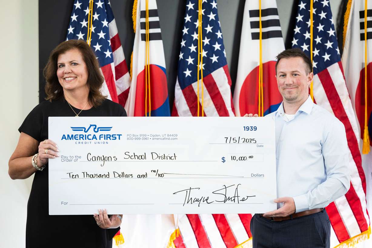 Amber Shill, left, District 2 president of the Canyons School District Board of Education, and Alex Racine, branch manager of America First Credit Union’s Draper branch, hold a check that will go toward a scholarship during a sister city welcome and celebration dinner for the bond between Cottonwood Heights, Utah, and Incheon, Yeonsu-gu, South Korea, held at the Cottonwood Heights City Hall on Saturday.