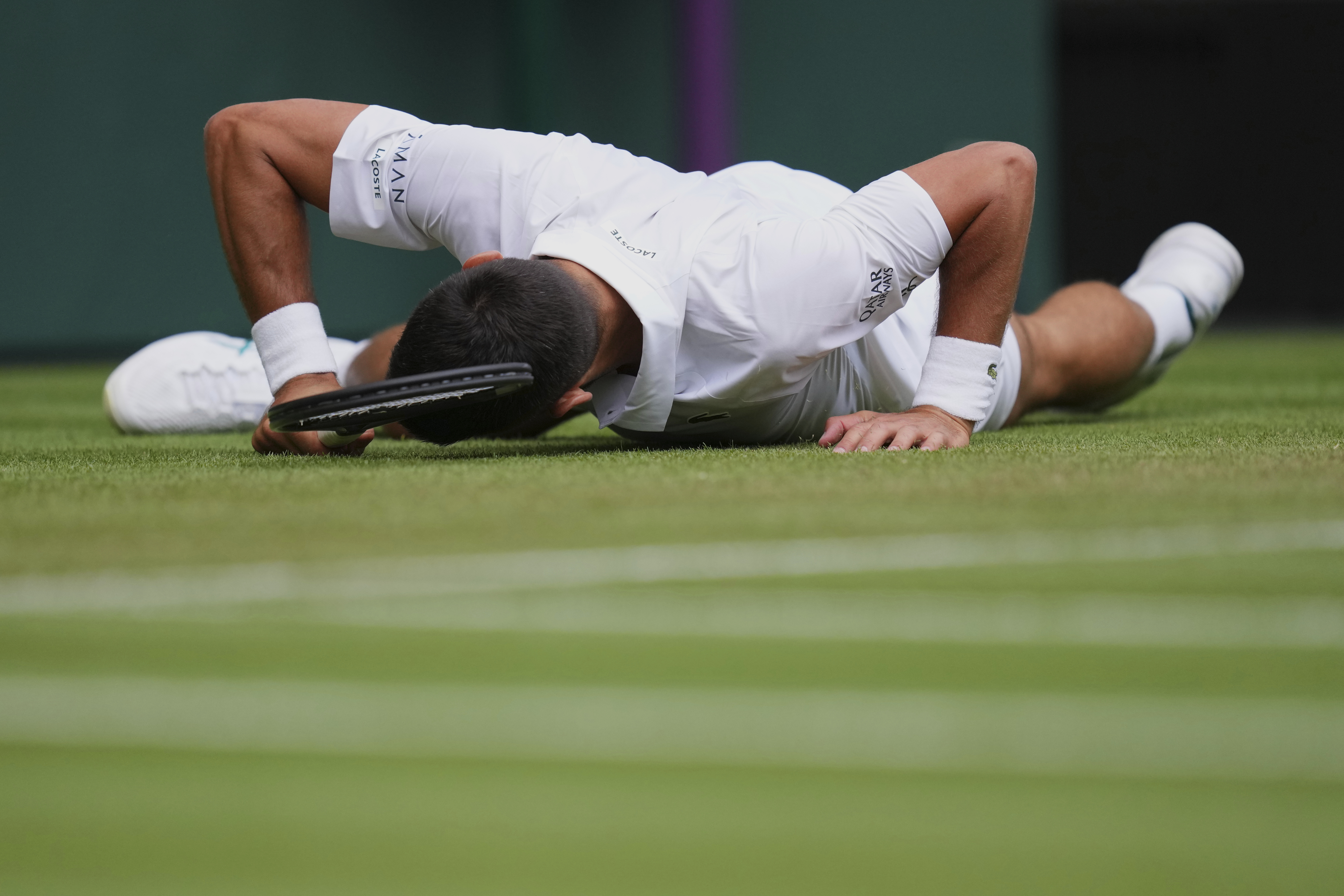 Novak Djokovic of Serbia slips and fall as he plays Miomir Kecmanovic of Serbia during a third round men's singles match at the Wimbledon Tennis Championships in London, Saturday, July 5, 2025.