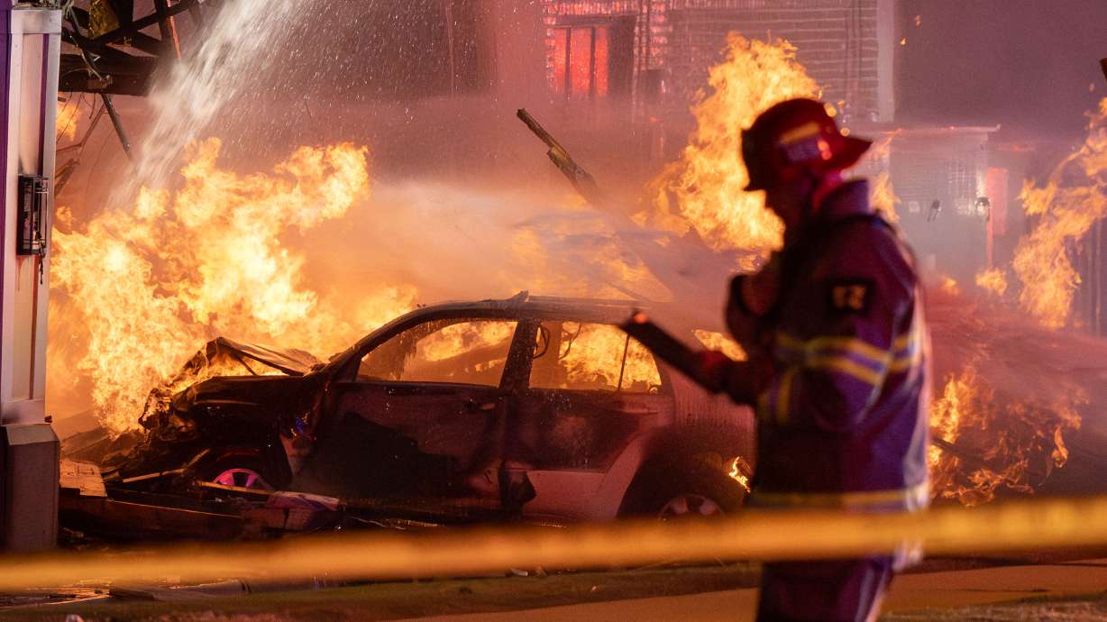 A vehicle burns as first responders from multiple agencies respond to a crash and gas explosion at Domino's Pizza in Herriman late Saturday.